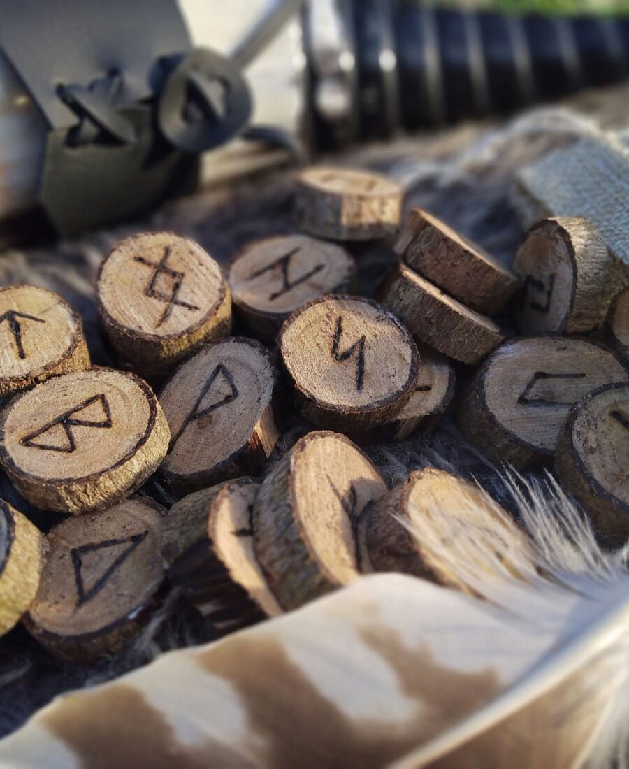 Pierres runiques en bois gravées, posées sur une fourrure avec une plume, pour l'article sur les runes et le Futhark