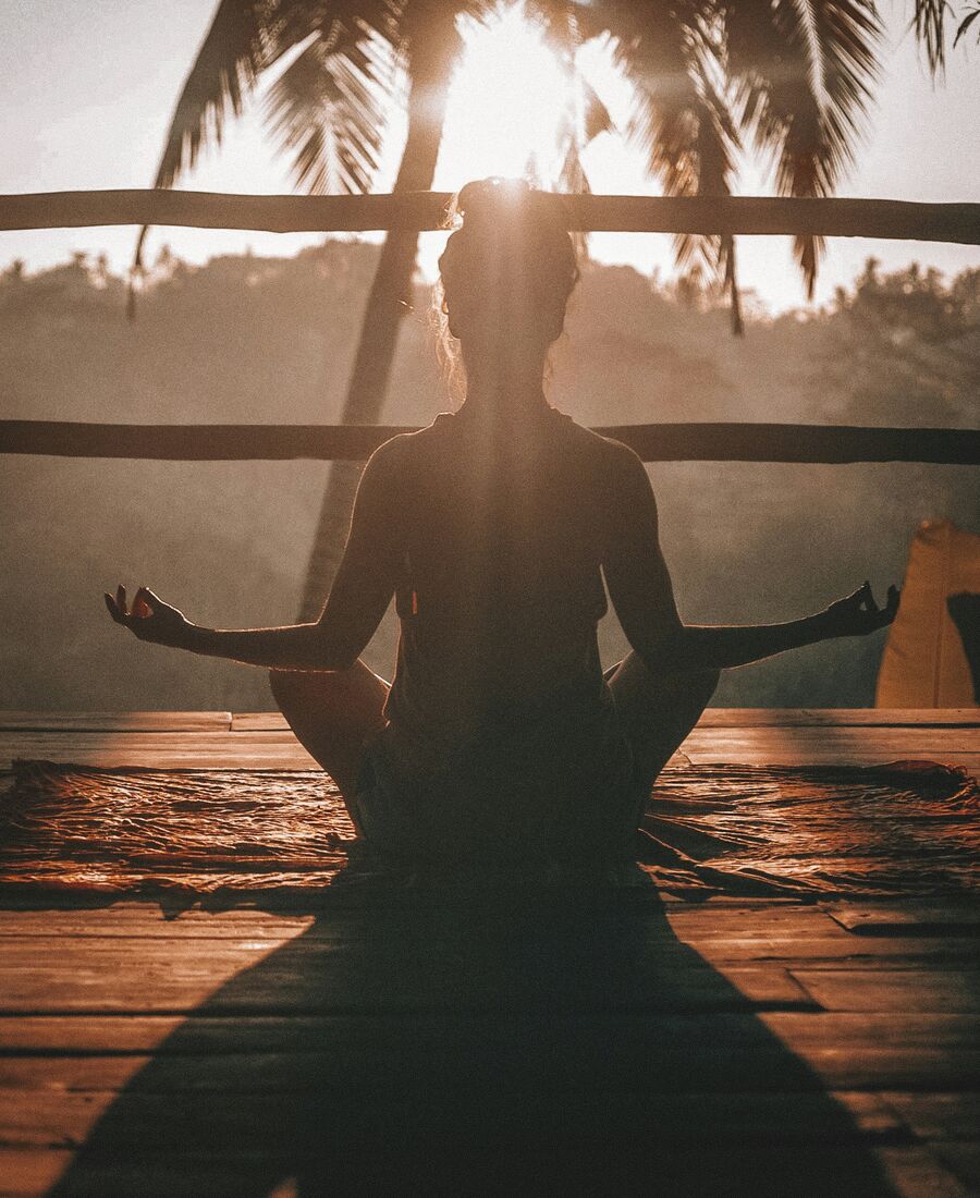 Silhouette en méditation face au soleil levant, symbole du sanctuaire holistique reliant corps, âme et esprit